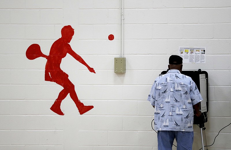 A voter casts a ballot next to a mural of a tennis player at a polling site in a school gymnasium in Atlanta, Tuesday, Nov. 7, 2017. Voters electing a new mayor for Atlanta and filling a handful of vacancies in the Georgia Legislature will find no shortage of choices on the ballot. (AP Photo/David Goldman)