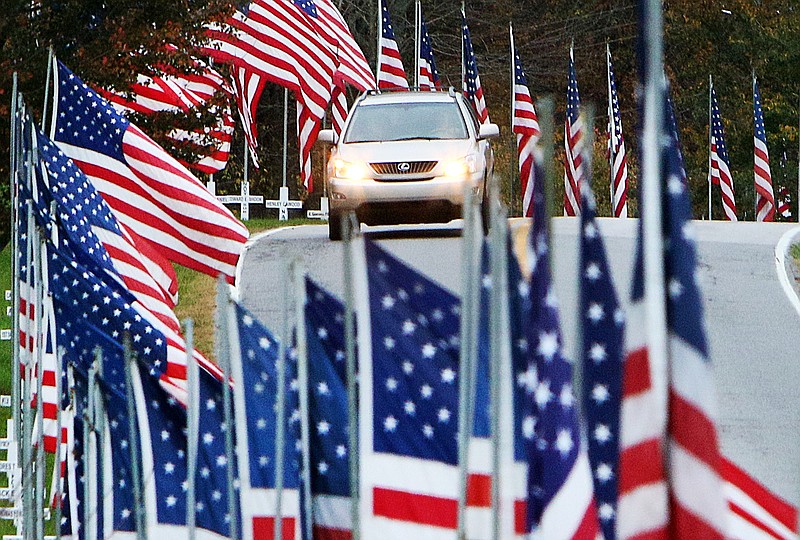 A car drives through American flags Wednesday Nov. 8, 2017, along Robin Road in Ringgold, Ga. Twice each year, the week before Memorial Day and the week before Veterans Day, volunteers place American flags along Ringgold's streets and highways to honor the county's fallen veterans.