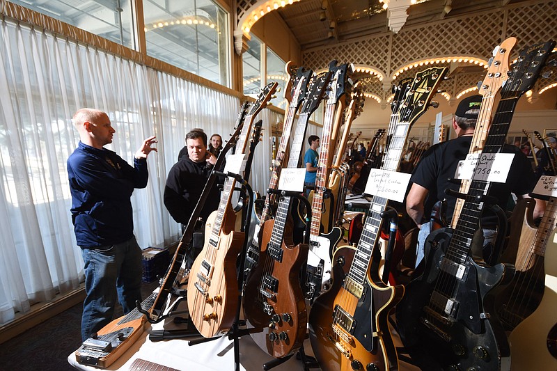 Kevin Aslinger, left, and Scott Balch talk about, and view dozens of guitars Saturday at the Guitaranooga expo in the Roosevelt Room at the Chattanooga Choo Choo.