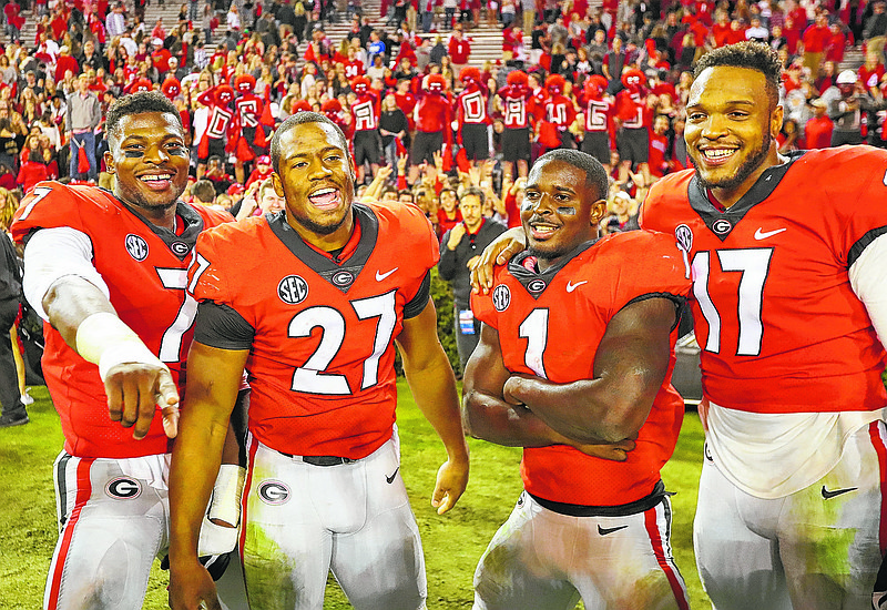 Georgia seniors, from left, Lorenzo Carter, Nick Chubb, Sony Michel, and Davin Bellamy celebrate their 42-13 victory over Kentucky  in an NCAA college football game, Saturday, Nov. 18, 2017, in Athens, Ga. (Curtis Compton/Atlanta Journal-Constitution via AP)
