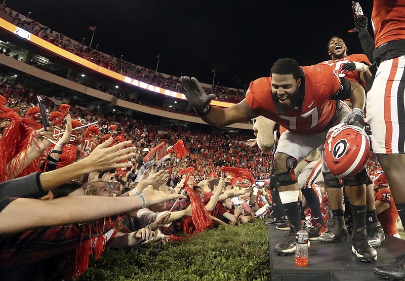 Georgia offensive tackle Isaiah Wynn (77) celebrates with fans after defeating Kentucky 42-13 in an NCAA college football game Saturday, Nov. 18, 2017, in Athens, Ga. (AP Photo/John Bazemore)