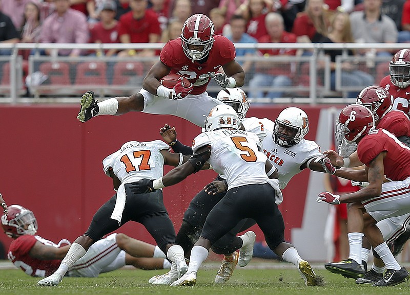 Alabama running back Najee Harris leaps over Mercer defensive back Eric Jackson (17) during the first half of an NCAA college football game, Saturday, Nov. 18, 2017, in Tuscaloosa, Ala. (AP Photo/Brynn Anderson)