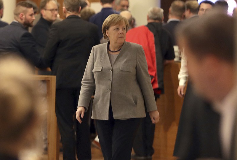 German Chancellor and chairwomen of the German Christian Democratic Union (CDU), Angela Merkel, center, walks in lobby of the representation of the German state of Baden-Wuerttemberg during exploratory talks on a coalition between the CDU, the Christian Social Union (CSU), the German Liberal Party (FDP) and the Green Party in Berlin, Germany, Sunday, Nov. 19, 2017. (AP Photo/Michael Sohn)