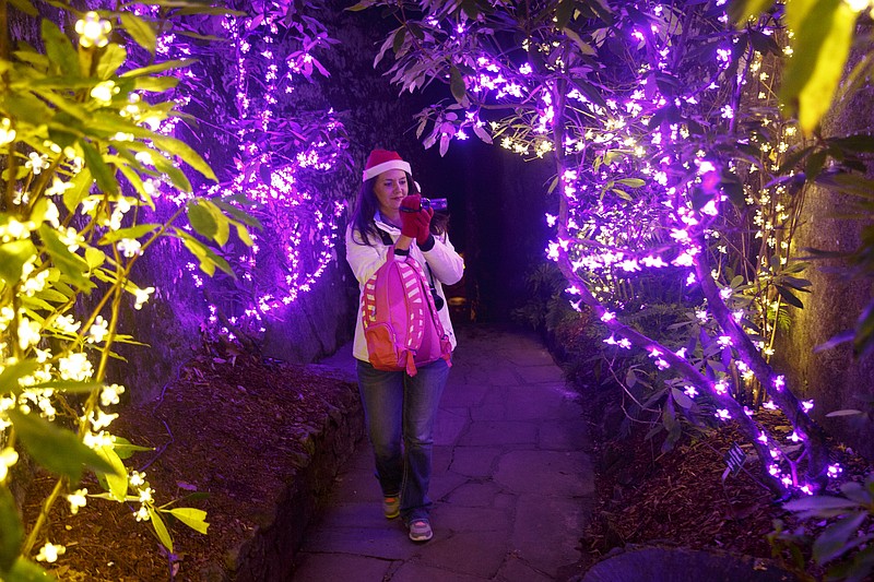 A visitor videos her walk along a lit path in Rocky City's Enchanted Garden of Lights.