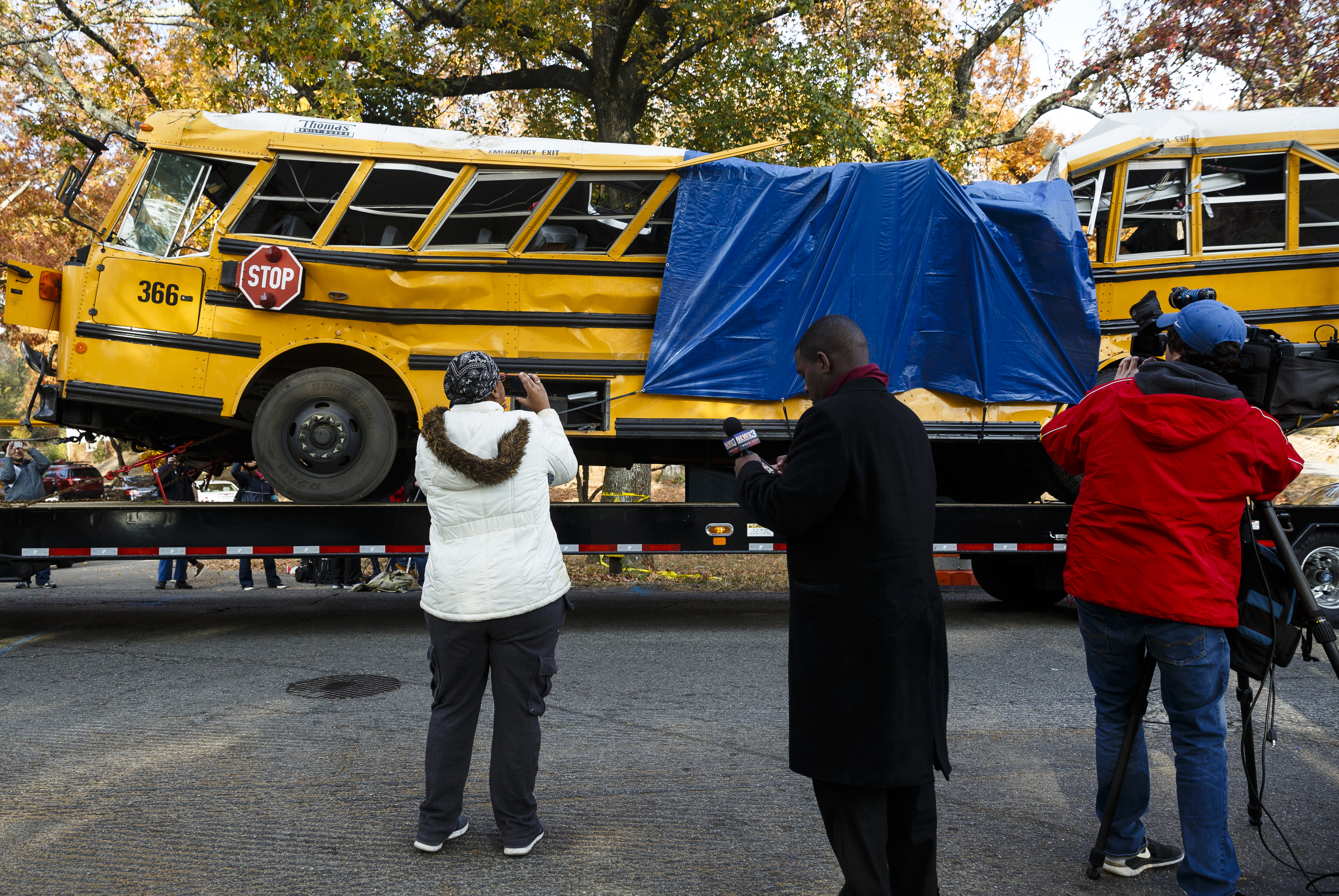 Neighborhood residents and media watch as a wrecker removes the school bus from the scene of a crash on Talley Road on Tuesday, Nov. 22, 2016, in Chattanooga, Tenn. The Monday afternoon crash killed at least 5 elementary schoolchildren and injured dozens more. The NTSB has been called in to help investigate.