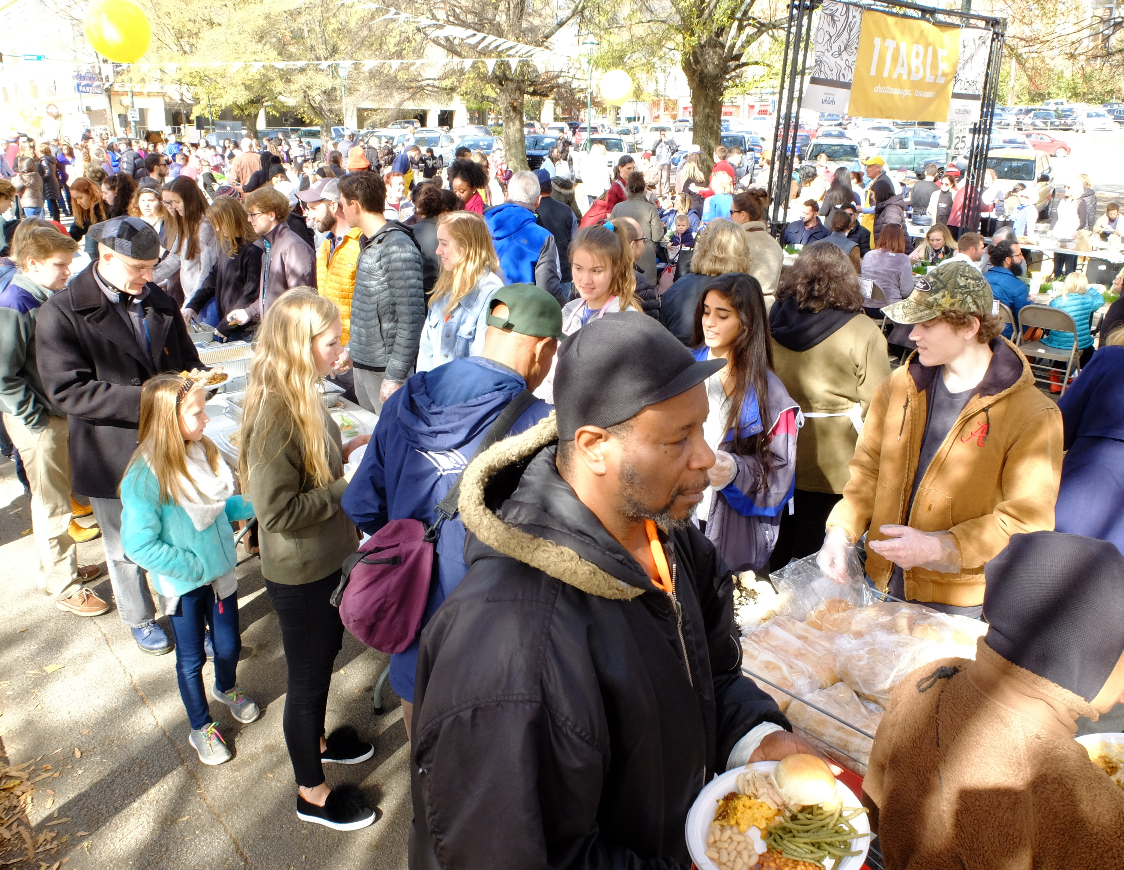 David Monroe, font center, carries away his plate of food as Scott Donahue, from top right, Khadija Aslam and Meg Marshall serve bread at one of many serving tables Monday, Nov. 20, in front of the Bessie Smith Cultural Center.