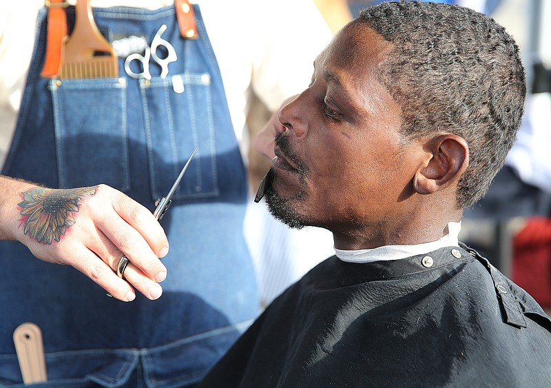 Mitchell Fuqua, a barber at All City Barber Company, trims Tim Green's beard Monday, Nov. 20, 2017, in front of Muse + Metta in Chattanooga, Tenn. The owner Muse + Metta and employees of All City Barber Company got together to give individuals free haircuts across from the Chattanooga Community Kitchen Monday afternoon. All City Barber Company had a couple of employees who volunteered from 1 p.m. until 4 p.m. cutting the hair of about 35 individuals Monday. 