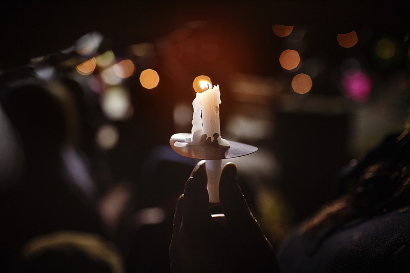 A woman holds a candle during a community vigil to remember victims of last year's Hamilton County school bus crash on Talley Road on Tuesday, Nov. 21, 2017, in Chattanooga, Tenn. Parents, friends, and supporters gathered near the spot where one year ago Tuesday, six children from Woodmore Elementary School were killed after bus 366 overturned on the residential street.