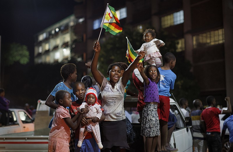 Zimbabweans celebrate at night at an intersection in downtown Harare, Zimbabwe Tuesday, Nov. 21, 2017. Mugabe resigned as president with immediate effect Tuesday after 37 years in power, shortly after parliament began impeachment proceedings against him. (AP Photo/Ben Curtis)