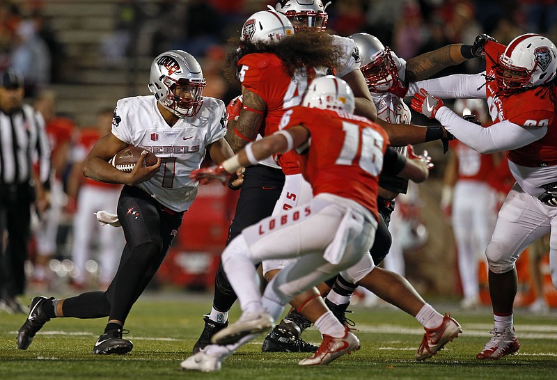 UNLV quarterback Armani Rogers, left, tries to get past the New Mexico defense during the second half of an NCAA college football game in Albuquerque, N.M., Friday, Nov. 17, 2017. (AP Photo/Andres Leighton)