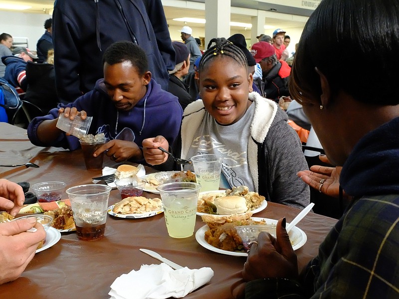 Jamaya Leftwic smiles as she listens to her grandmother Shirley Fennell, near right, during lunch at the Community Kitchen Thursday. Fennell's son, Jeremy Fennell, left, listens to the exchange as he puts more ice in his cup.