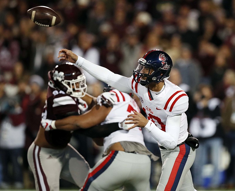 Mississippi quarterback Jordan Ta'amu, right, passes as a Mississippi State defender rushes him during the first half of an NCAA college football game in Starkville, Miss., Thursday, Nov. 23, 2017. (AP Photo/Rogelio V. Solis)