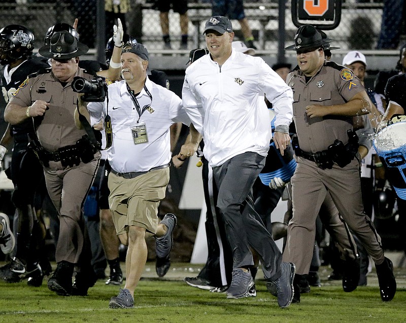 Central Florida coach Scott Frost, center, runs onto the field after the team defeated South Florida 49-42 in an NCAA college football game, Friday, Nov. 24, 2017, in Orlando, Fla. (AP Photo/John Raoux)