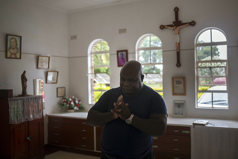 
              Fidelis Mukonori, a Catholic priest who mediated talks with Zimbabwe's former President Robert Mugabe, prays inside the sacristy after mass in Chishawasha, Sunday, Nov. 26, 2017.  Mugabe knew it was "the end of the road" days before he quit, and appeared relieved when he signed his resignation letter after 37 years in power, a Catholic priest who mediated talks leading to his ouster said Sunday. (AP Photo/Bram Janssen)
            