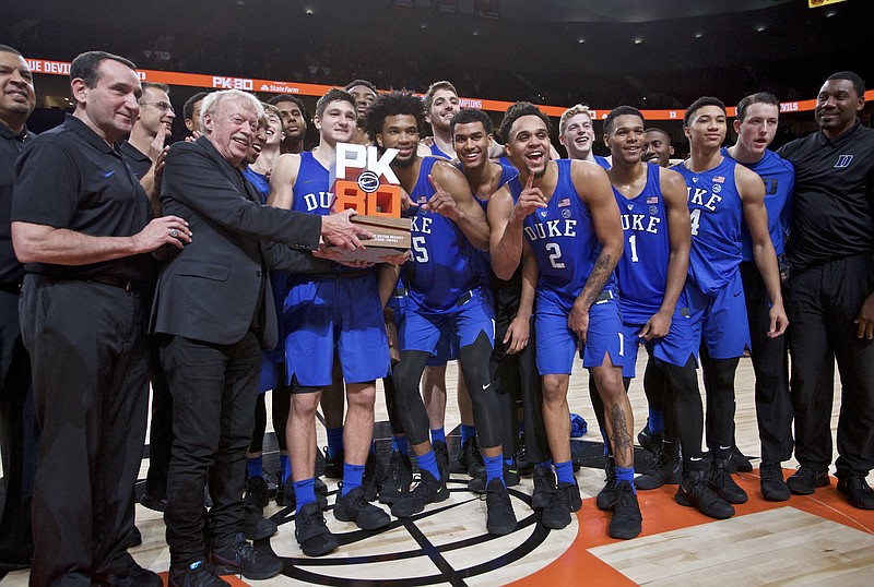 Nike founder Phil Knight presents the championship trophy to Duke head coach Mike Krzyzewski, left, after an NCAA college basketball game against Florida in the Phil Knight Invitational tournament in Portland, Ore., Sunday, Nov. 26, 2017. Duke won 87-84. (AP Photo/Craig Mitchelldyer)