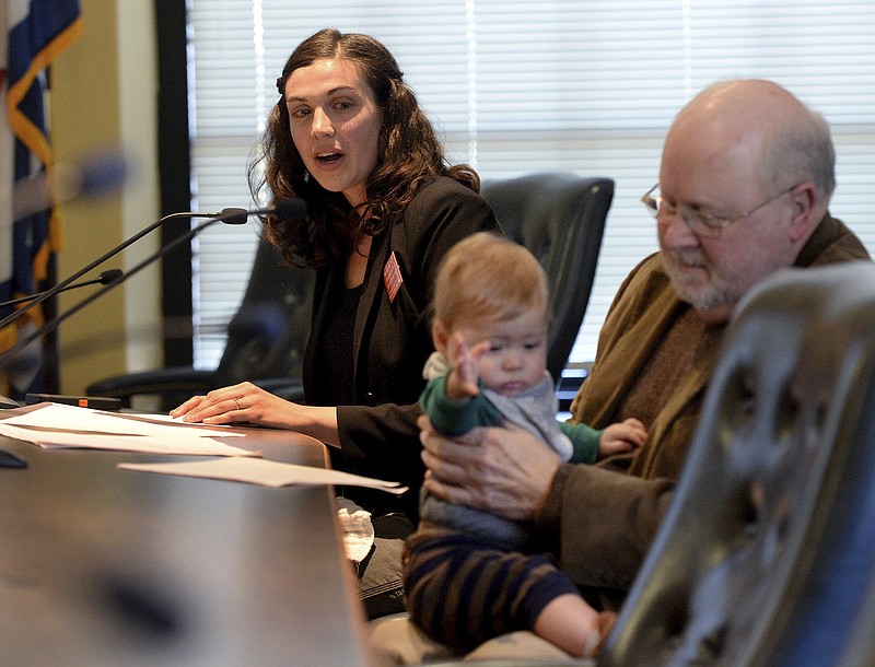 Lindsay Pace, left, of Chattanooga Tenn., testifies as as retired coal miner and mine inspector Stanley Sturgill of Lynch Ky., holds Pace's son Theo, during an Environmental Protection Agency public hearing, Tuesday, Nov. 28, 2017, at the state Capitol in Charleston, W.Va. The EPA was taking comments Tuesday and Wednesday on its proposed repeal of the Clean Power Plan, an Obama-era plan to limit planet-warming carbon emissions. Pace and Sturgill spoke against repealing the Obama administration's Clean Power Plan (Chris Dorst/Charleston Gazette-Mail via AP)