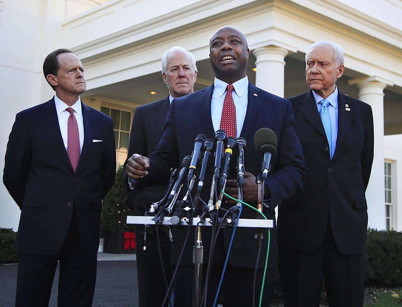 Senate Finance Committee member Sen. Tim Scott, R-S.C., front, with, from left, Sens. Patrick Toomey, R-Pa., John Cornyn, R-Texas, and Chairman Orrin Hatch, R-Utah, speaks to reporters following a meeting with President Donald Trump at the White House in Washington, Monday, Nov. 27, 2017. (AP Photo/Manuel Balce Ceneta)