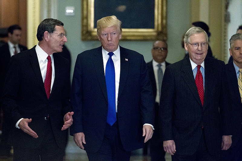 President Donald Trump, center, escorted by Sen. John Barrasso, R-Wyo., chairman of the Senate Republican Policy Committee, left, and Senate Majority Leader Mitch McConnell, R-Ky., right, arrives at the Capitol to meet with GOP lawmakers about moving his agenda and passing the Republican tax bill, in Washington, Tuesday, Nov. 28, 2017. ( AP Photo/Jose Luis Magana)