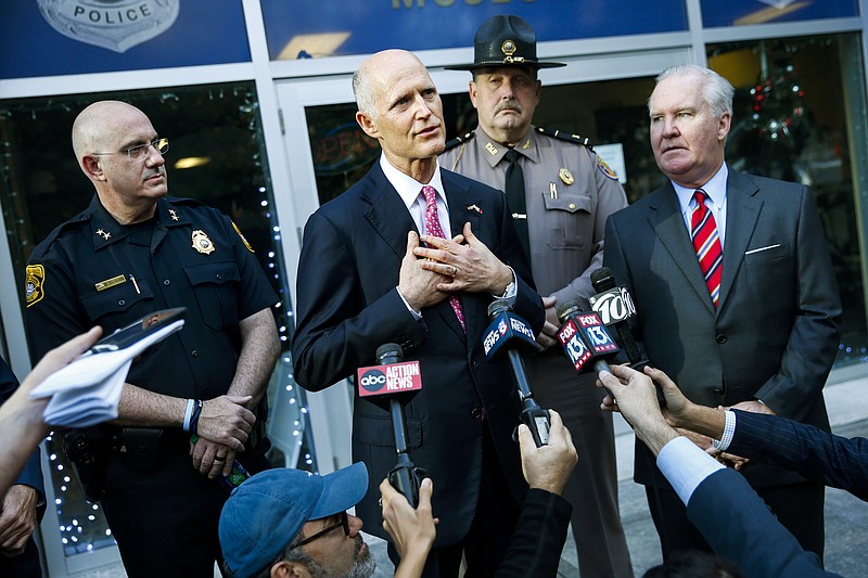 Florida Gov. Rick Scott, center, with Tampa Police Chief Brian Dugan, left, and Tampa Mayor Bob Buckhorn, right, talks with members of the media at Tampa Police Headquarters in Tampa, Fla., Wednesday, Nov. 29, 2017. Scott's visit followed the announcement of the arrest in the Seminole Heights murders. (Will Vragovic/Tampa Bay Times via AP)