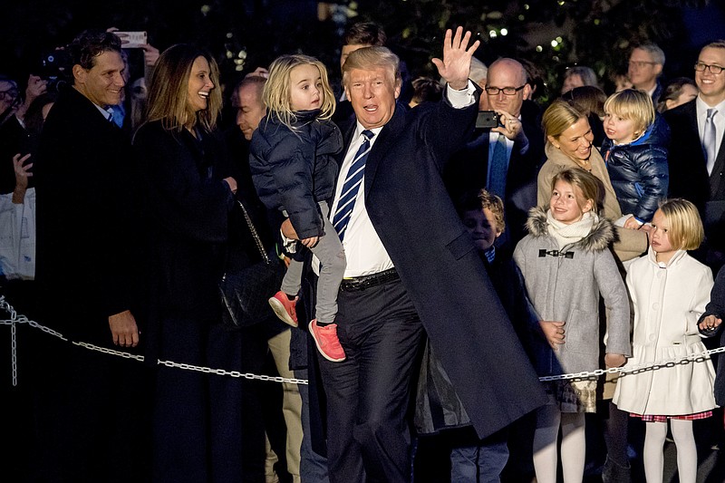 President Donald Trump holds a girl in his arm and waves to members of the media as he arrives at the White House in Washington, Saturday, Dec. 2, 2017, after traveling to New York for fundraising events. (AP Photo/Andrew Harnik)