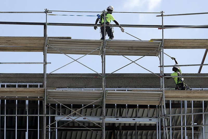 In this Friday, Oct. 6, 2017, photo, workers build an apartment and retail complex in Nashville, Tenn. Economists expect a tax overhaul to provide a modest boost to the U.S. economy but are increasingly worried that a rewrite of the North American Free Trade Agreement will take a toll on growth. (AP Photo/Mark Humphrey)