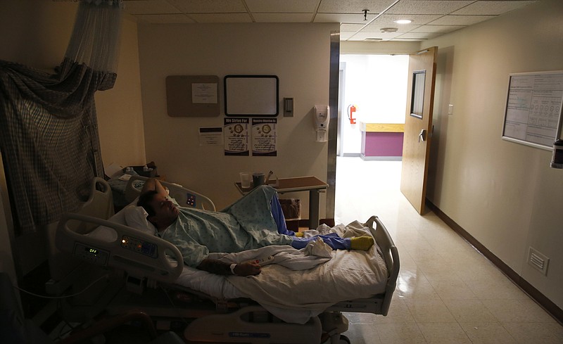 In this Tuesday, Oct. 24, 2017, photo, Richard Rivera lies in his Saint Anthony Hospital bed a few days after arriving sick from heroin withdrawal in Chicago. His public health insurance would cover three days in the hospital's new medical detox unit. Hours later, just moments from going to a sober-living facility, Rivera complained of chest pains that took him away from the watchful eye of the medical detox staff. (AP Photo/Charles Rex Arbogast)