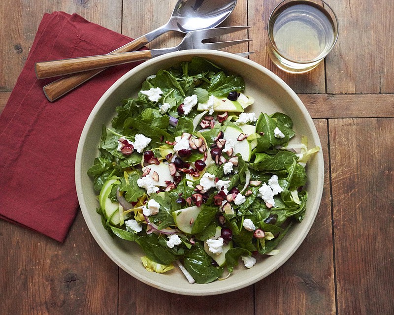 This October 2017 photo shows a winter green salad with cranberries and goat cheese in New York. This salad comes together in 20 minutes, and is a bowl of vibrant color and texture that seems anything but a postscript to the menu. (Mia via AP)