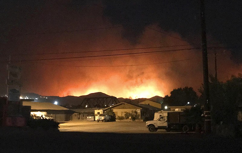 Flames from a wildfire loom up over a neighborhood in Santa Paula, Calf., Monday, Dec. 4, 2017. Ventura County fire officials say the blaze broke out Monday east of Santa Paula, a city of 30,000 people about 60 miles northwest of downtown Los Angeles. Powerful winds are pushing the blaze west toward the city along Highway 150, which is shut down. (Megan Diskin/The Ventura County Star via AP)