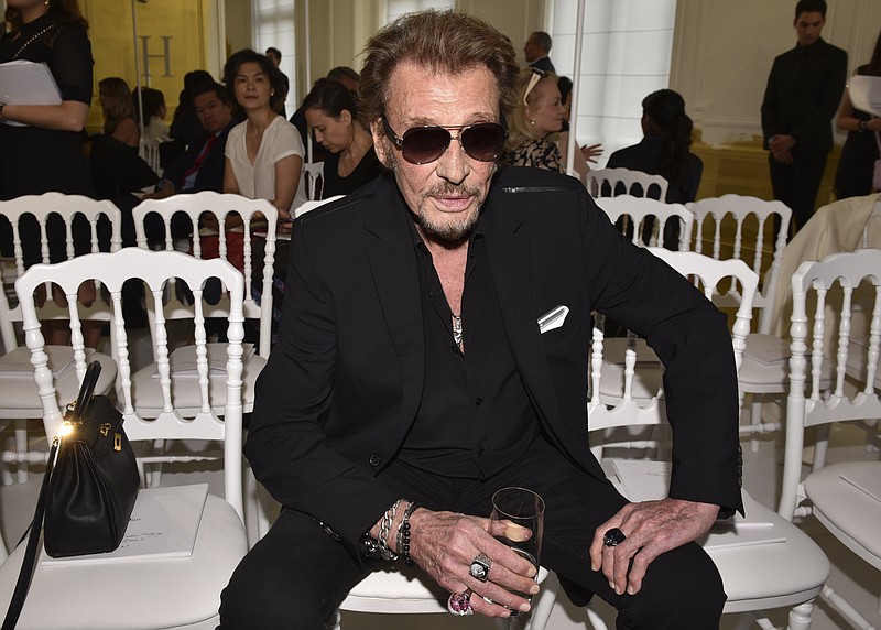 In this July 4, 2016, file picture, French rock singer Johnny Hallyday waits before Christian Dior's Haute Couture Fall-Winter 2016-2017 fashion collection presented in Paris, France. The French president's office says Hallyday, who packed sports stadiums for decades, has died at age 74. (AP Photo/Zacharie Scheurer, File)