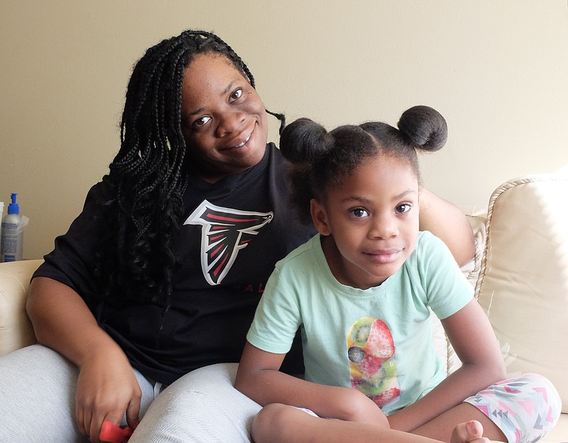 Althea Banks, left, and her daughter, Monica, sit on the couch in their home.