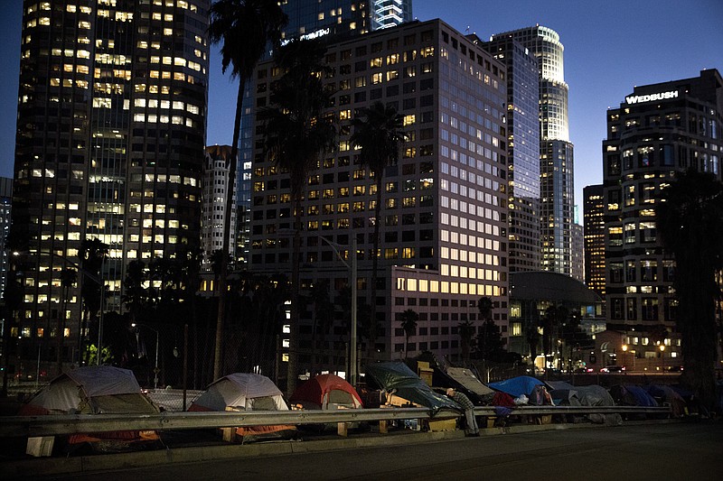 Homeless tents are dwarfed by skyscrapers as 63-year-old Vincent, who only gave his first name, sorts his belongings Friday, Dec. 1, 2017, in Los Angeles.