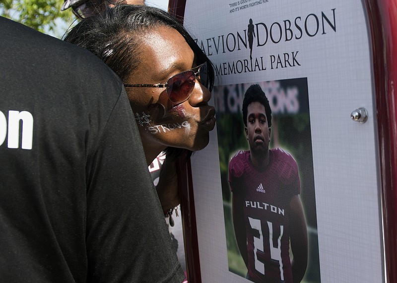 In this April 26, 2017, file photo, Zenobia Dobson kisses a photograph of her son, Zaevion Dobson, that serves as the memorial marker for a new playground named and dedicated in his honor in Knoxville, Tenn. A prosecutor said Tuesday, Dec. 5, at start of the murder trial of three young men that at least 34 shots were fired in an attack that killed the Tennessee high school student who was posthumously lauded for courageously shielding two girls from the gunfire. (Saul Young/Knoxville News Sentinel via AP, File)