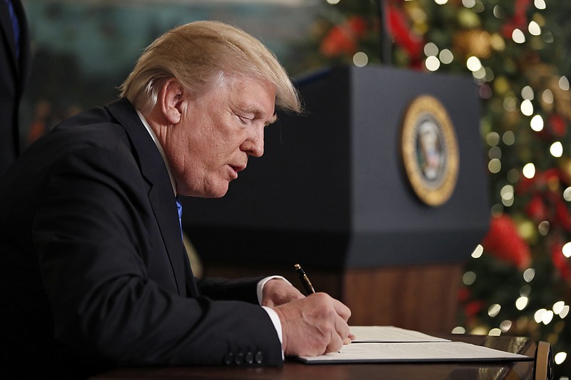 President Donald Trump signs a proclamation in the Diplomatic Reception Room of the White House, Wednesday, Dec. 6, 2017, in Washington. 