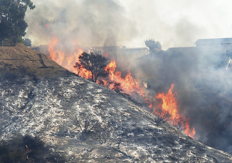 Flames sweep up a steep canyon wall, threatening homes on a ridge line as the Skirball wildfire swept through the Bel Air district of Los Angeles Wednesday, Dec. 6, 2017. (AP Photo/Reed Saxon)