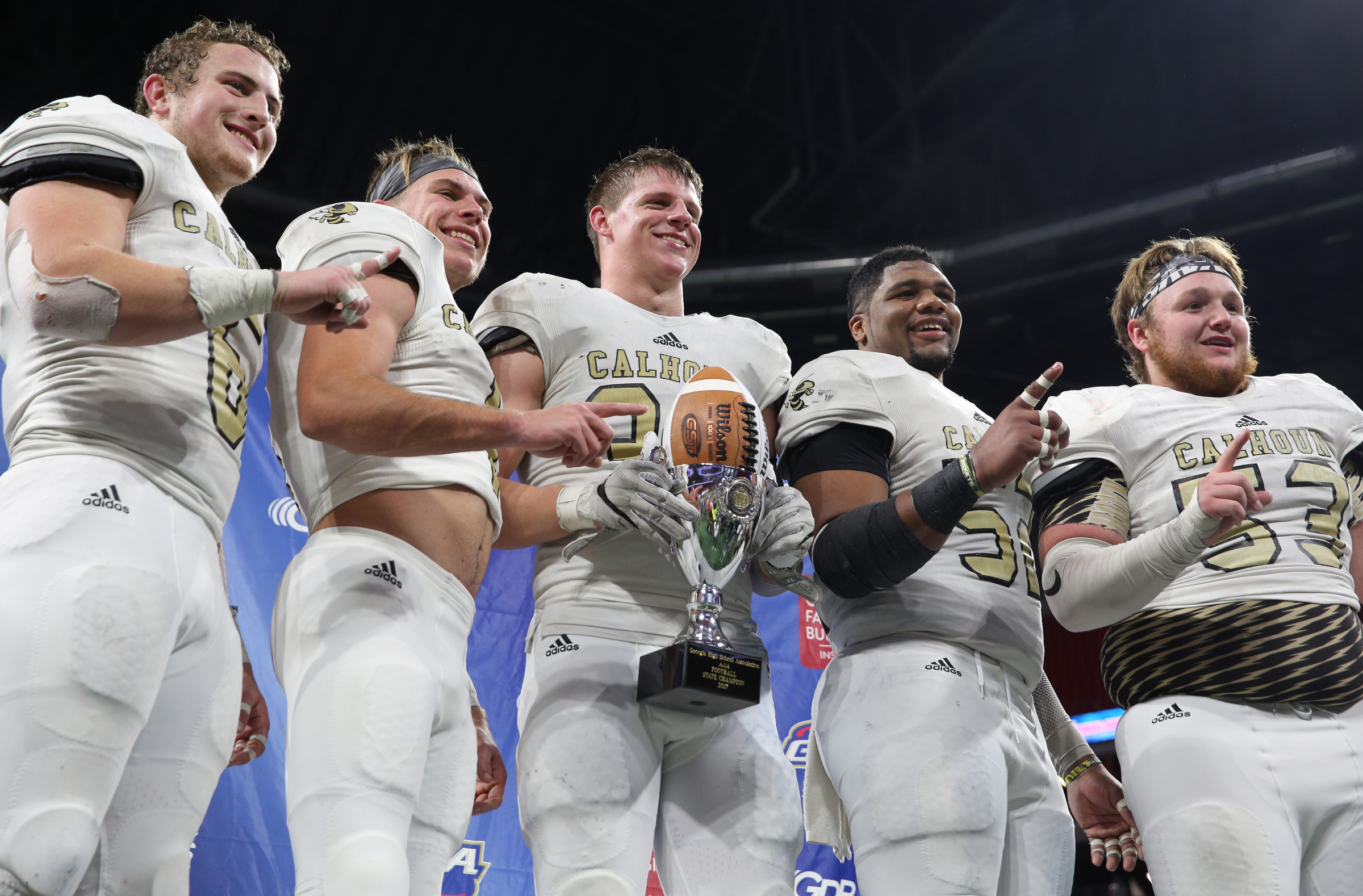 Calhoun's Bailey Lester (6), Porter Law (1), Zeke Nance (33), C.J. Fuller (52) and J.C. Fuller (54) stand on stage with their trophy for a photo following their Class AAA State Championship win against Peach County Friday, Dec. 8, 2017 at Mercedes-Benz Stadium in Atlanta, Ga.
