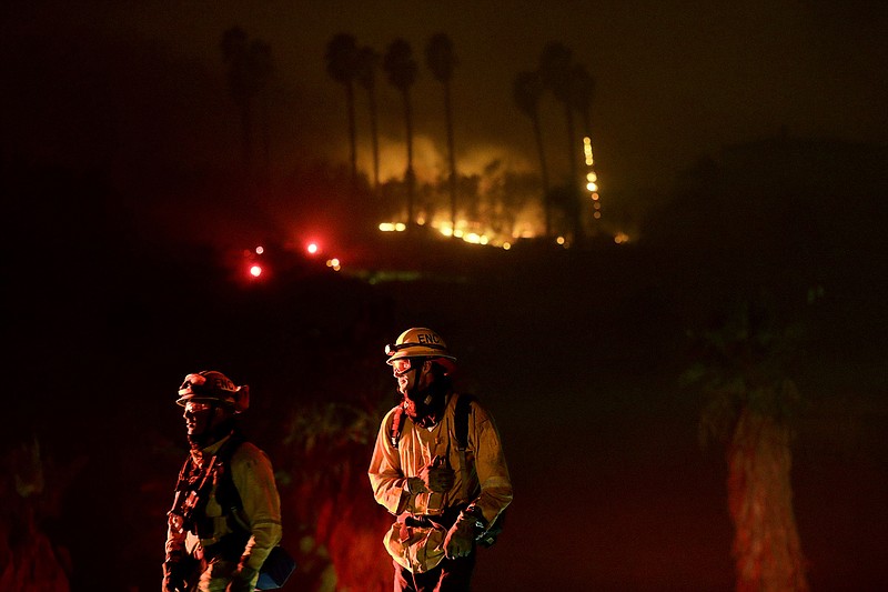 Fire crews look on as they fight a wildfire Thursday, Dec. 7, 2017, in Bonsall, Calif. The wind-swept blazes have forced tens of thousands of evacuations and destroyed dozens of homes in Southern California. (AP Photo/Gregory Bull)