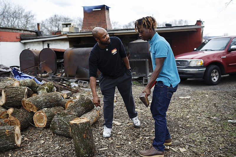 Owner Javan Martin talks with Gabriel Moore as he splits wood behind Sunset BBQ on Dodson Avenue on Thursday, Dec. 7, 2017, in Chattanooga, Tenn. Martin works with neighborhood children to help keep them occupied and teach them work and life skills. He also pays them to help around the restaurant by chopping wood, cleaning grills and doing other odd jobs. Moore says he comes nearly every day.