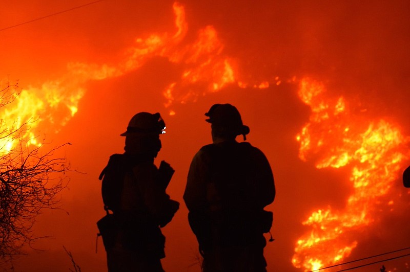 In this early morning Sunday, Dec. 10, 2017 photo released by Santa Barbara County Fire Department, firefighters working on structure protection, keep a close eye on nearby flames atop Shepard Mesa Road in Carpinteria, Calif. The area has been evacuated by law enforcement and FD has moved in to protect homes. in Carpinteria, Calif. A flare-up on the western edge of Southern California's largest and most destructive wildfire sent residents fleeing Sunday, as wind-fanned flames churned through canyons and down hillsides toward coastal towns. Crews with help from water-dropping aircraft saved several homes as unpredictable gusts sent the blaze churning deeper into foothill areas northwest of Los Angeles that haven't burned in decades. New evacuations were ordered in Carpinteria, a seaside city in Santa Barbara County that has been under fire threat for days. (Mike Eliason/Santa Barbara County Fire Department via AP)