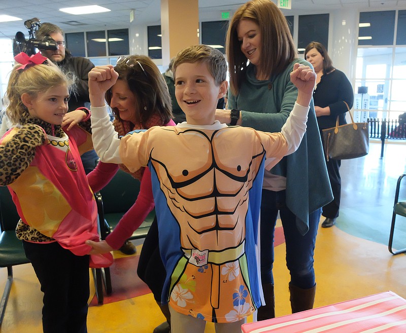 In the Children's Hospital at Erlanger lobby, Colin Sanders, 11, sports a new surfer hospital gown designed for patients. Colin was diagnosed with neuroblastoma 10 years ago at the hospital. From left are Molly Ransom, 8, Wendy Ransom, Colin and his mother, Mindy Sanders.