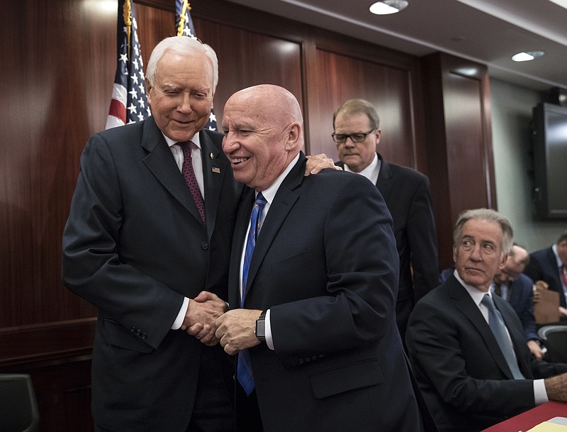 House Ways and Means Committee Chairman Kevin Brady, R-Texas, center, embraces Senate Finance Committee Chairman Orrin Hatch, R-Utah, left, as House and Senate conferees after GOP leaders announced they have forged an agreement on a sweeping overhaul of the nation's tax laws, on Capitol Hill in Washington, Wednesday, Dec. 13, 2017.