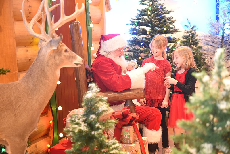 Santa offers candy cane to Carlie Kennedy, left, 9, and Sophia Farris, both of Fort Oglethorpe Wednesday at Bass Pro Shop in East Ridge.
