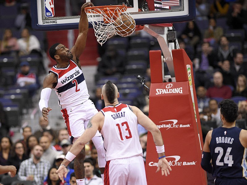 Washington Wizards guard John Wall (2) dunks during the first half of an NBA basketball game against the Memphis Grizzlies, Wednesday, Dec. 13, 2017, in Washington. Also seen is Wizards center Marcin Gortat (13) and Grizzlies forward Dillon Brooks (24). (AP Photo/Nick Wass)