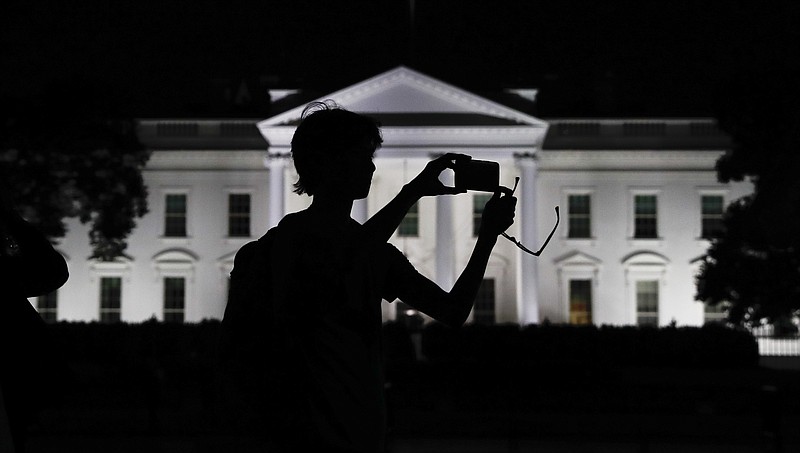 FILE - In this Aug. 25, 2017, file photo, a tourist takes a photo from Pennsylvania Avenue of the illuminated White House in Washington.