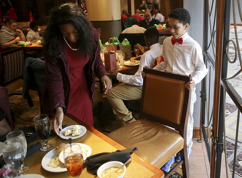 Twelve-year-old Keyshawn Castro pulls out a chair for Jamaya Tipton, 12, during the Guys and Ties, Girls and Pearls event at Broad Street Grill in The Chattanoogan on Friday, Dec. 15, 2017 in Chattanooga, Tenn. The event was organized by Chattanooga Public Safety Coordinator Troy Rogers and offered Orchard Knob Middle School students a fine dining experience.