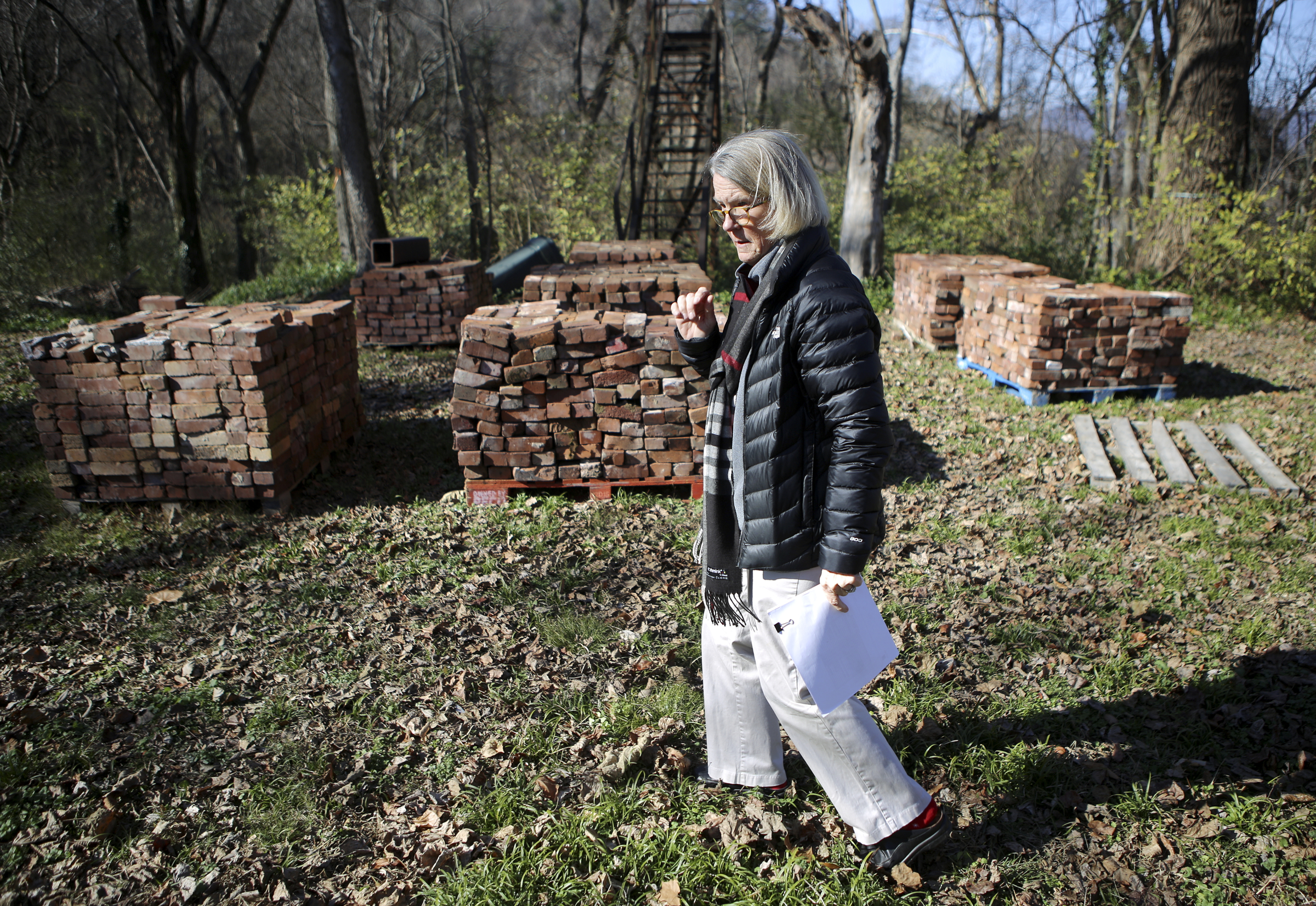 Lookout Mountain Conservancy Executive Director Robyn Carlton gives a tour of the location of the old Scholze mansion off of Old Wauhatchie Pike on Thursday, Dec. 14, 2017 in Chattanooga, Tenn. Stacked behind Carlton are some of the 36,000 bricks recovered from the property. The Lookout Mountain Conservancy plans to create a conservation-themed neighborhood of 24 homes on 3.5 acres at the site of the old Scholze home place.