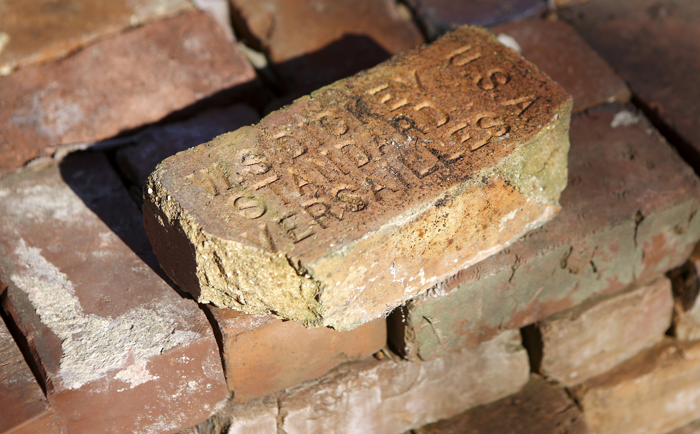 A brick recovered from the site of the former Scholze family estate off of Old Wauhatchie Pike is seen with the stamped words "W.S. DICKEY STANDARD VERSAILLES U.S.A." on Thursday, Dec. 14, 2017 in Chattanooga, Tenn. The Lookout Mountain Conservancy plans to create a conservation-themed neighborhood of 24 homes on 3.5 acres at the site of the old Scholze home place.