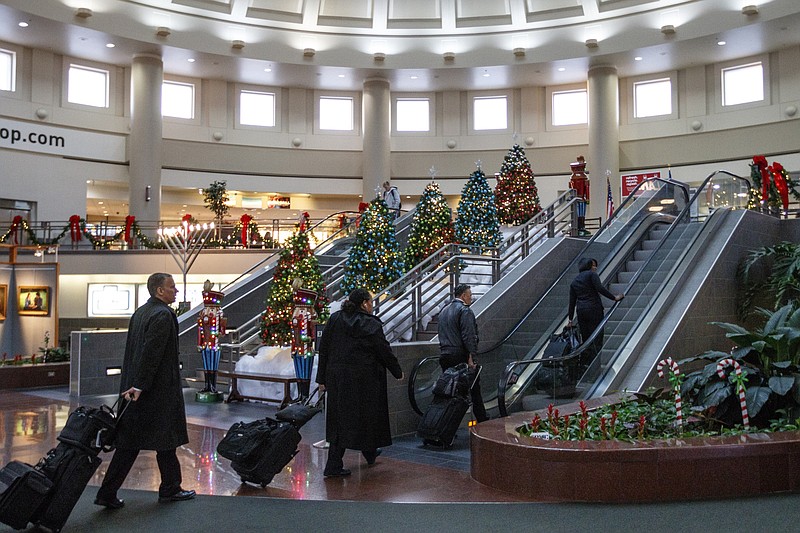 Travelers walk past rows of Christmas trees while traveling through the Chattanooga Metropolitan Airport on Friday, Dec. 15, 2017, in Chattanooga, Tenn. AAA forecasts a 3.1% increase in holiday travel over last year with an estimated 103 million Americans traveling between Dec. 23rd and Jan. 1st.