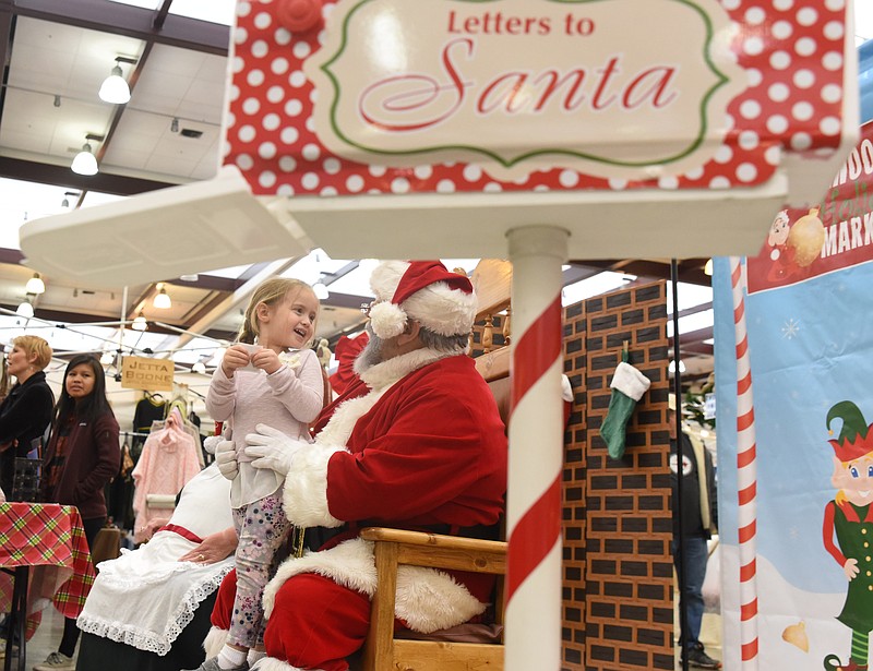 Emma Shealey, 3, smiles as she tells Santa her wishes Sunday inside the Chattanooga Convention Center at the Chattanooga Christmas Market.