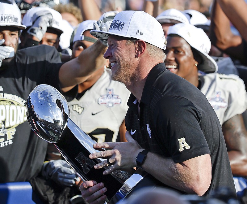 FILE - In this Dec. 2, 2017, file photo, Central Florida head coach Scott Frost holds the winning trophy after defeating Memphis in the American Athletic Conference championship NCAA college football game, in Orlando, Fla. Scott Frost is The Associated Press coach of the year after leading UCF to an unbeaten season and a spot in the Peach Bowl. (AP Photo/John Raoux, File)