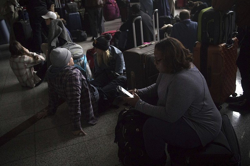 Passengers wait for the lights to come back on at Hartsfield-Jackson International Airport Sunday, Dec. 17, 2017. Authorities say a power outage at the Hartsfield-Jackson Atlanta International Airport has disrupted ingoing and outgoing flights. Airport spokesman Reese McCraine says the outage occurred early Sunday afternoon. He says all airport operations are being affected and that outgoing flights were halted. (Steve Schaefer/Atlanta Journal-Constitution via AP)